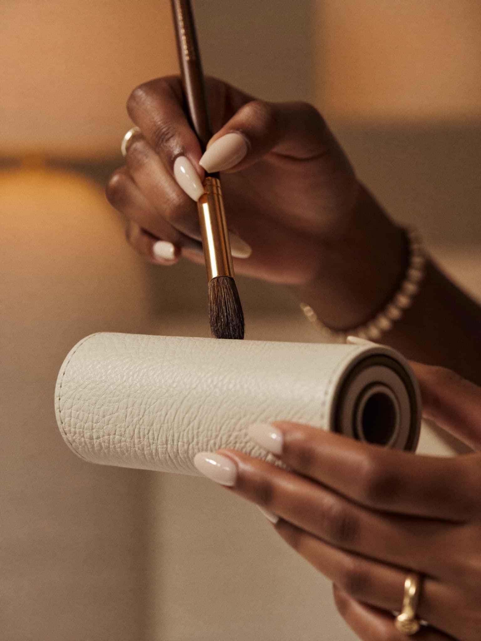 Makeup artist's hands selecting a brush from a leather brush roll