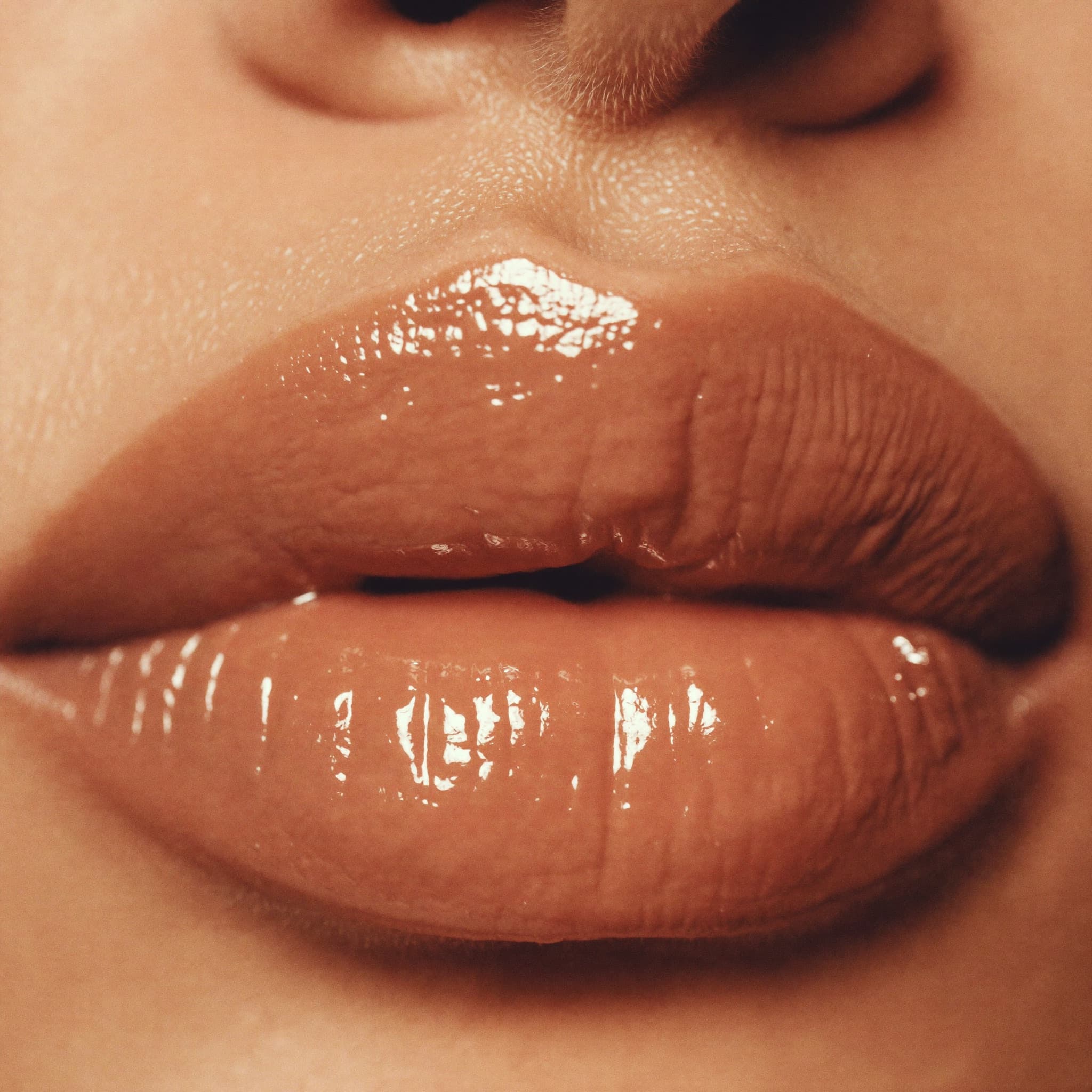 Macro beauty close-up of a warm nude glossy lip