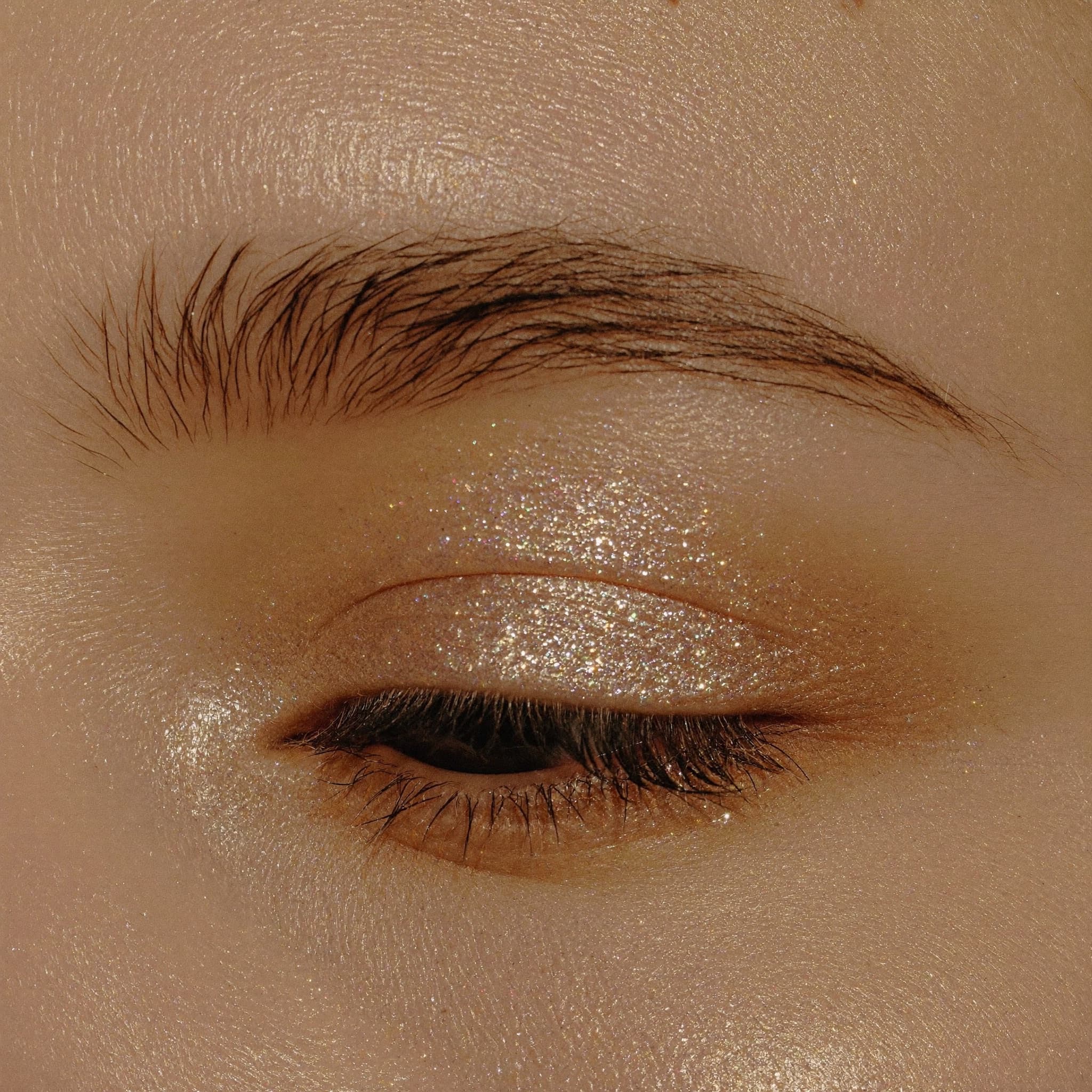 Macro close-up of champagne shimmer eyeshadow and defined lashes