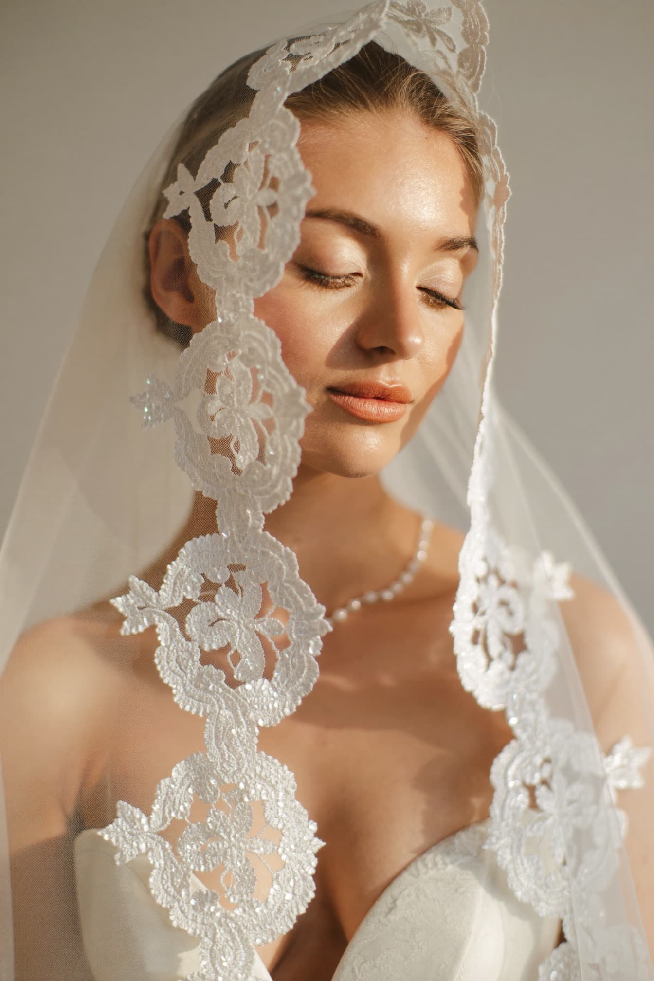 Bride with soft, timeless makeup and a delicate veil in natural light