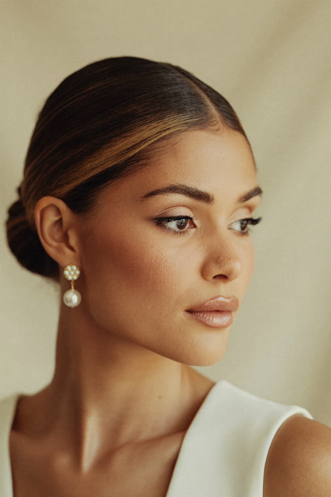 Bridal profile with low chignon, pearl earring and soft glam makeup