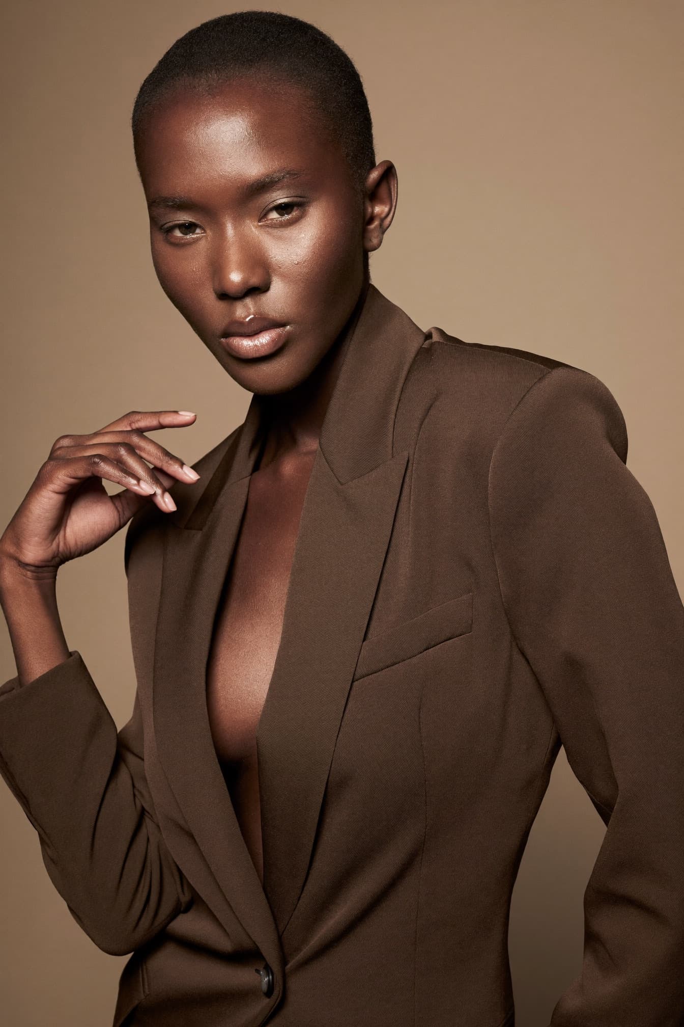 Fashion editorial look with sculpted bronze tones and a glossy nude lip